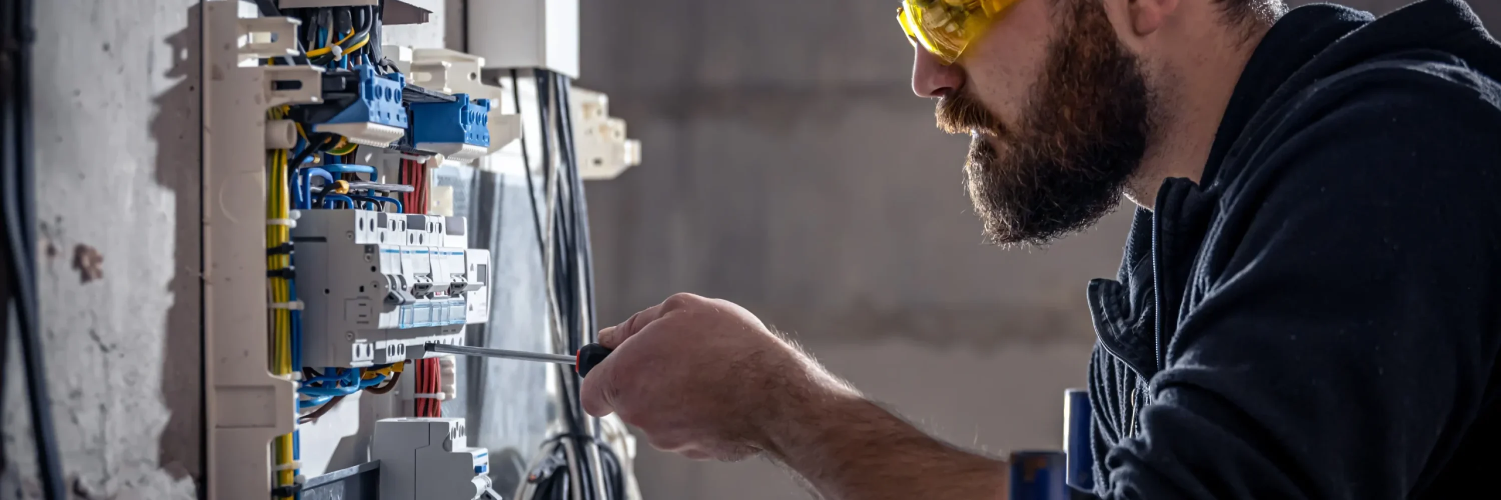 a-male-electrician-works-in-a-switchboard-with-an-2025-03-13-03-18-08-utc